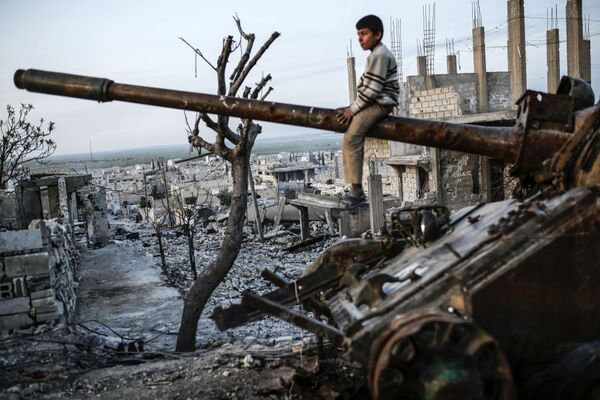 پسربچه کردی بر تانک تخریب شده در شهر کوبانی سوریه نشسته است - اسپوتنیک افغانستان  