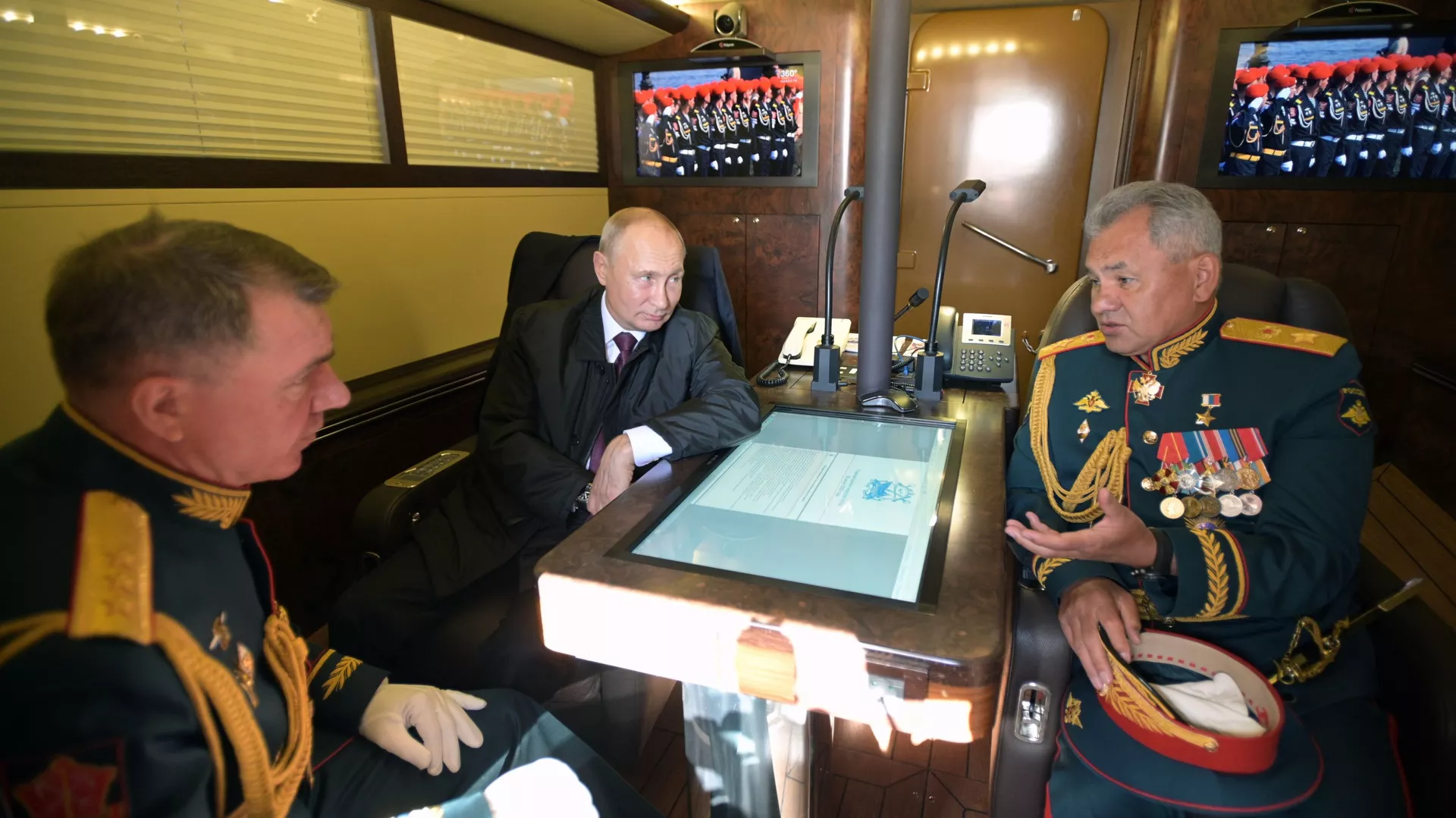 Президент РФ, верховный главнокомандующий Владимир Путин, министр обороны РФ Сергей Шойгу (справа) и командующий войсками Западного военного округа Александр Журавлев (слева) в каюте президентского катера во время перехода в акваторию Финского залива