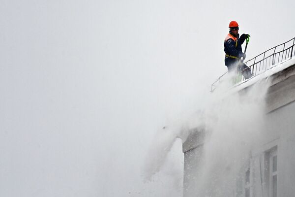 کارگر خدمات شهری هنگام پاک کردن برف از روی بام در مسکو - اسپوتنیک افغانستان  