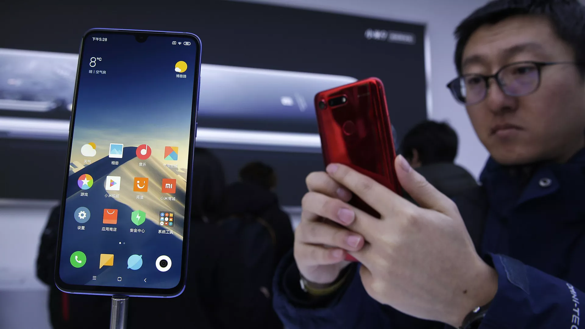An invited guest takes a photo of Xiaomi new model Mi 9 displayed on an exhibition booth after its launch event in Beijing, Wednesday, Feb. 20, 2019