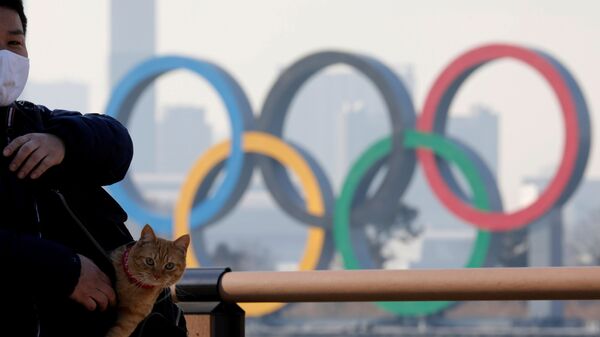 Мужчина с котом в сумке на фоне олимпийских колец в Токио - اسپوتنیک افغانستان  