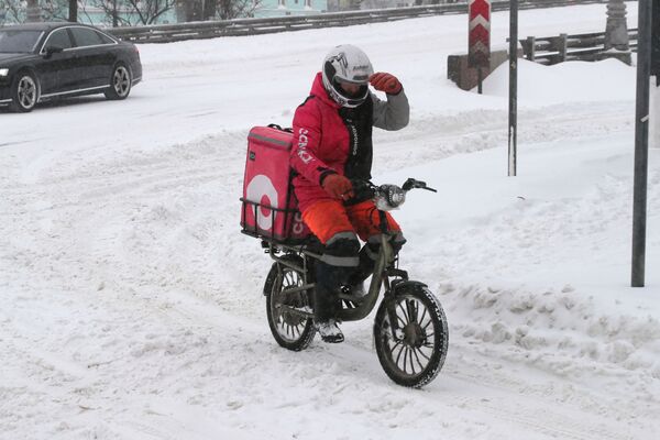کارمند خدمات، سوار بر بایسکل هنگام بارش برف در مسکو. - اسپوتنیک افغانستان  