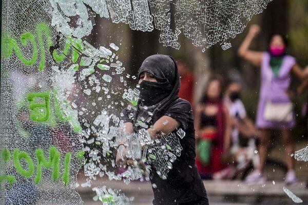 شکستن شیشه‌ها از سوی یک زن هنگام اعتراضات مکسیکو. - اسپوتنیک افغانستان  