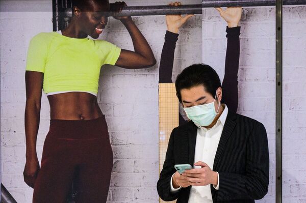 مردی با تلفن هوشمند در پس زمینه پوستر با یک دختر. - اسپوتنیک افغانستان  