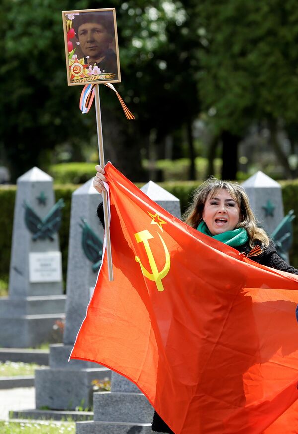 زنی با پرچم شوروی و تصویر یک جانباز در قبرستان اولشانسکی در پراگ، جمهوری چک - اسپوتنیک افغانستان  