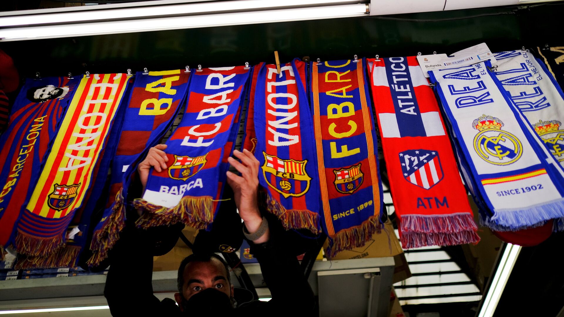 Soccer Football - FC Barcelona, Atletico Madrid and Real Madrid scarves are displayed inside a store at Las Ramblas as twelve of Europe's top football clubs launch a breakaway Super League - Barcelona, Spain - April 19, 2021 - اسپوتنیک افغانستان  , 1920, 21.03.2022
