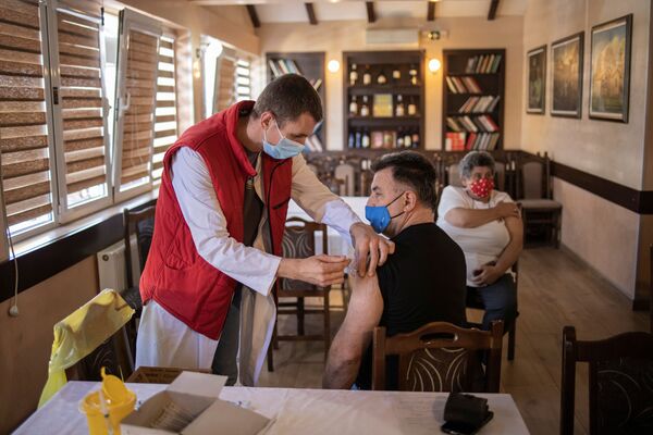 مردی هنگام دریافت، واکسین کرونا در صربستان. - اسپوتنیک افغانستان  