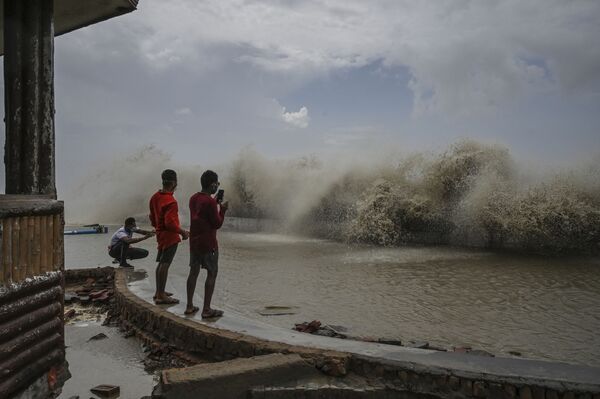 مردم محلی با رسیدن طوفان یااس به ساحل شرقی هند از موج های سقوط به ساحل عکس می گیرند. - اسپوتنیک افغانستان  