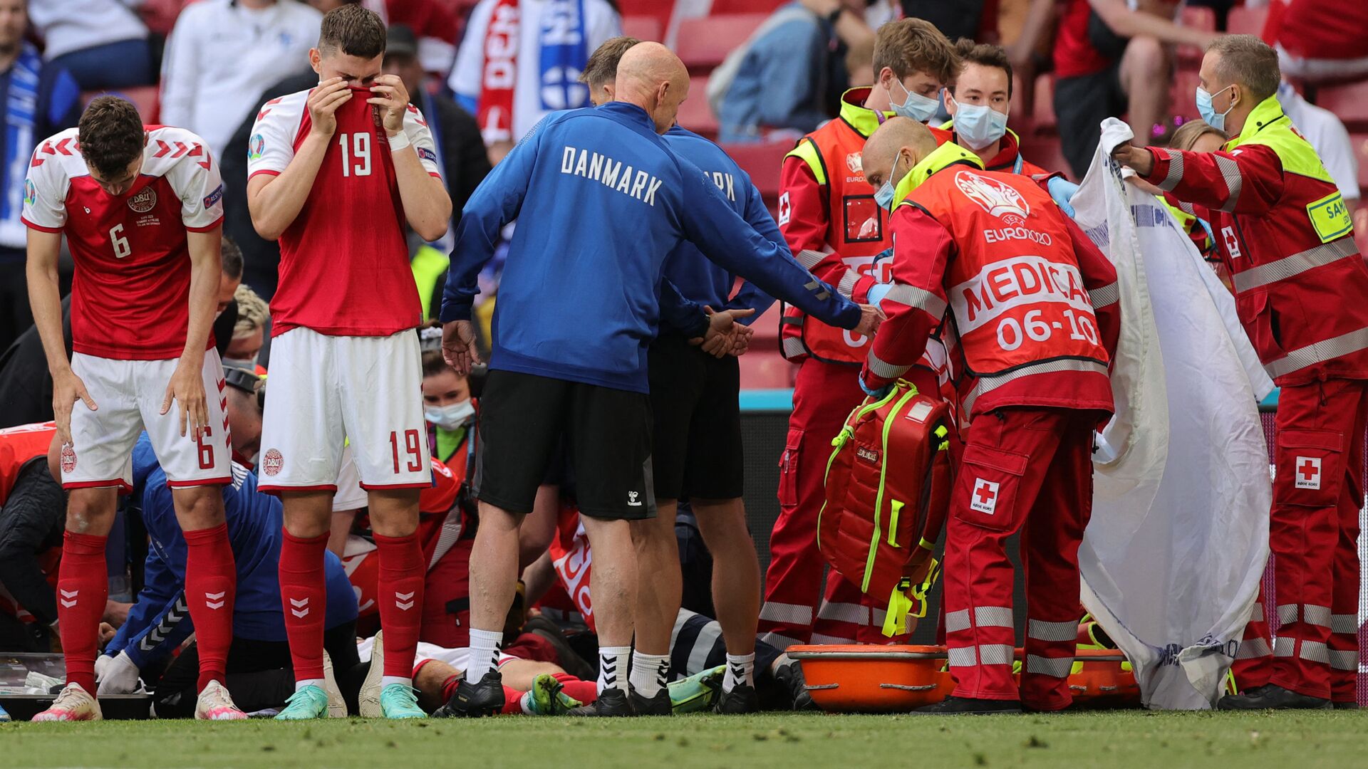 Denmark's players react as paramedics attend to Denmark's midfielder Christian Eriksen after he collapsed on the pitch during the UEFA EURO 2020 Group B football match between Denmark and Finland at the Parken Stadium in Copenhagen on June 12, 2021. - اسپوتنیک افغانستان  , 1920, 01.08.2021