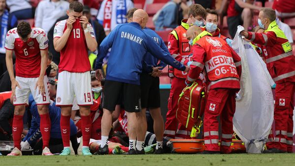 Denmark's players react as paramedics attend to Denmark's midfielder Christian Eriksen after he collapsed on the pitch during the UEFA EURO 2020 Group B football match between Denmark and Finland at the Parken Stadium in Copenhagen on June 12, 2021. - اسپوتنیک افغانستان  