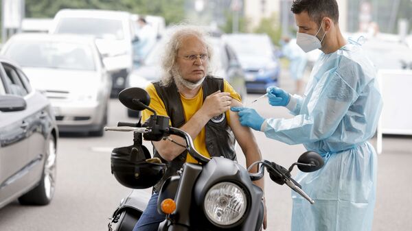 Медицинский работник применяет дозу вакцины против коронавируса в центре вакцинации для автомобилей в Берлине - اسپوتنیک افغانستان  