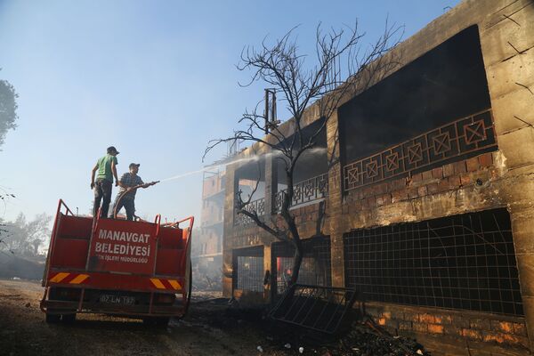 آتش نشانان در حال خاموش کردن خانه‌ای که در آتش سوزی های جنگلی در ماناگاوت ترکیه سوخته است. - اسپوتنیک افغانستان  