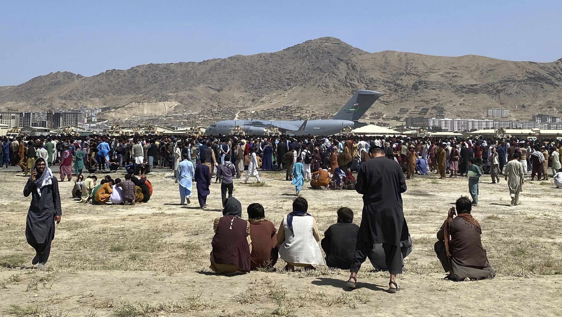  Hundreds of people gather near a U.S. Air Force C-17 transport plane at a perimeter at the international airport in Kabul, Afghanistan, Monday, Aug. 16, 2021 - اسپوتنیک افغانستان  , 1920, 17.08.2021
