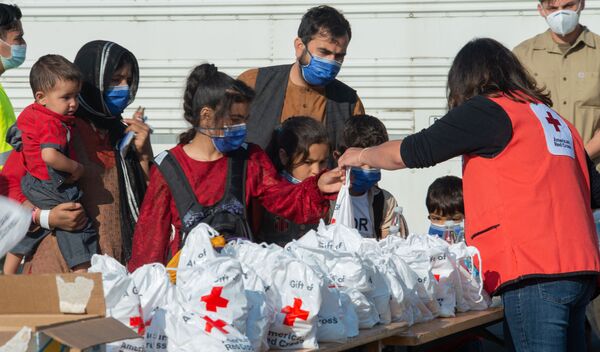 نمایندگان صلیب سرخ  هنگام کمک رسانی به کودکان پناهنده افغان. - اسپوتنیک افغانستان  