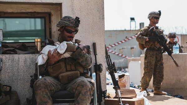 Морской пехотинец США с ребенком на руках во время эвакуации в международном аэропорту Кабула, Афганистан - اسپوتنیک افغانستان  