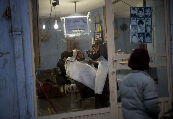 پسری به آرایشگاهی نگاه می کند که در آن ریش مردی را اصلاح میکنند/ کابل - سال 2013. - اسپوتنیک افغانستان  