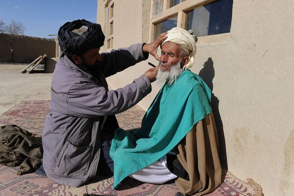 آرایشگر روستایی در حال تراشیدن ریش مردی در ولایت غزنی افغانستان در سال 2011. - اسپوتنیک افغانستان  