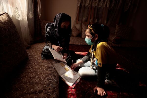سحر دختر 17 ساله که خواهر کوچکترش را در دروس مکتب کمک می‌کند. - اسپوتنیک افغانستان  