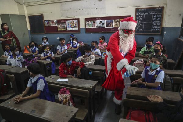 مردی در لباس بابانئل در مدرسه‌ی در هند مواد ضد عفونی توضیع می‌کند. - اسپوتنیک افغانستان  