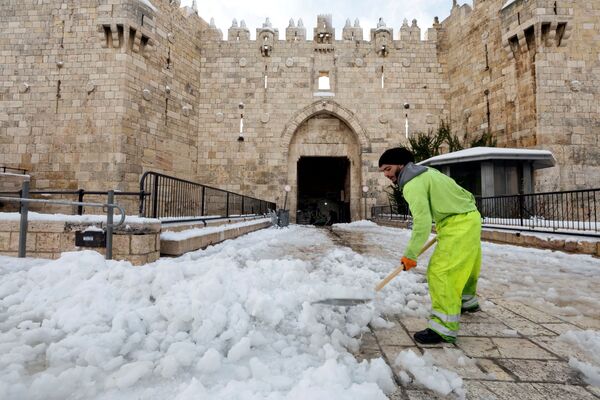 مردی درحال پاک کاری برف در مقابل دروازه قدیمی بیت‌المقدس. - اسپوتنیک افغانستان  