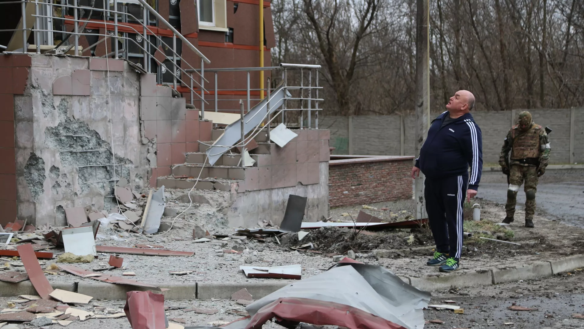 Житель города во дворе многоэтажного жилого дома в Донецке, поврежденного в результате обстрела