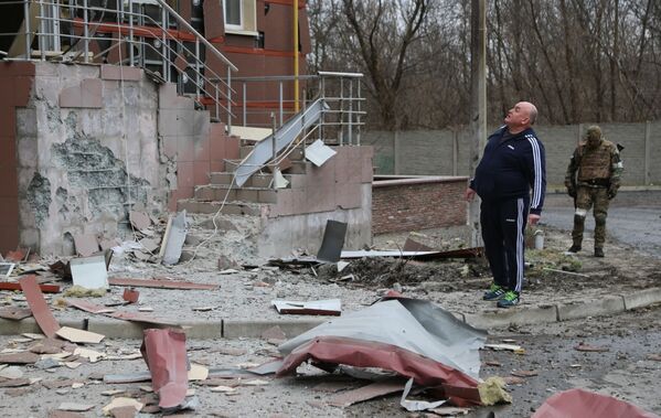 ساکن شهر دونتسک در کنار خانه ای که مورد اصابت گلوله ها قرار گرفته است. - اسپوتنیک افغانستان  