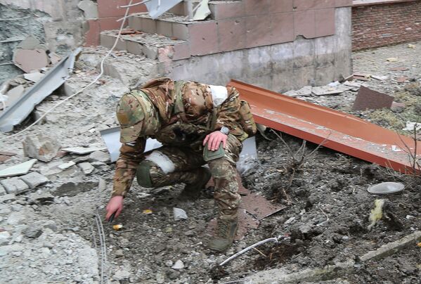 یک نظامی در حال بررسی دهانه ناشی از انفجار در حویلی یک ساختمان مسکونی چند طبقه در دونتسک که در اثر گلوله باران آسیب دیده است. - اسپوتنیک افغانستان  