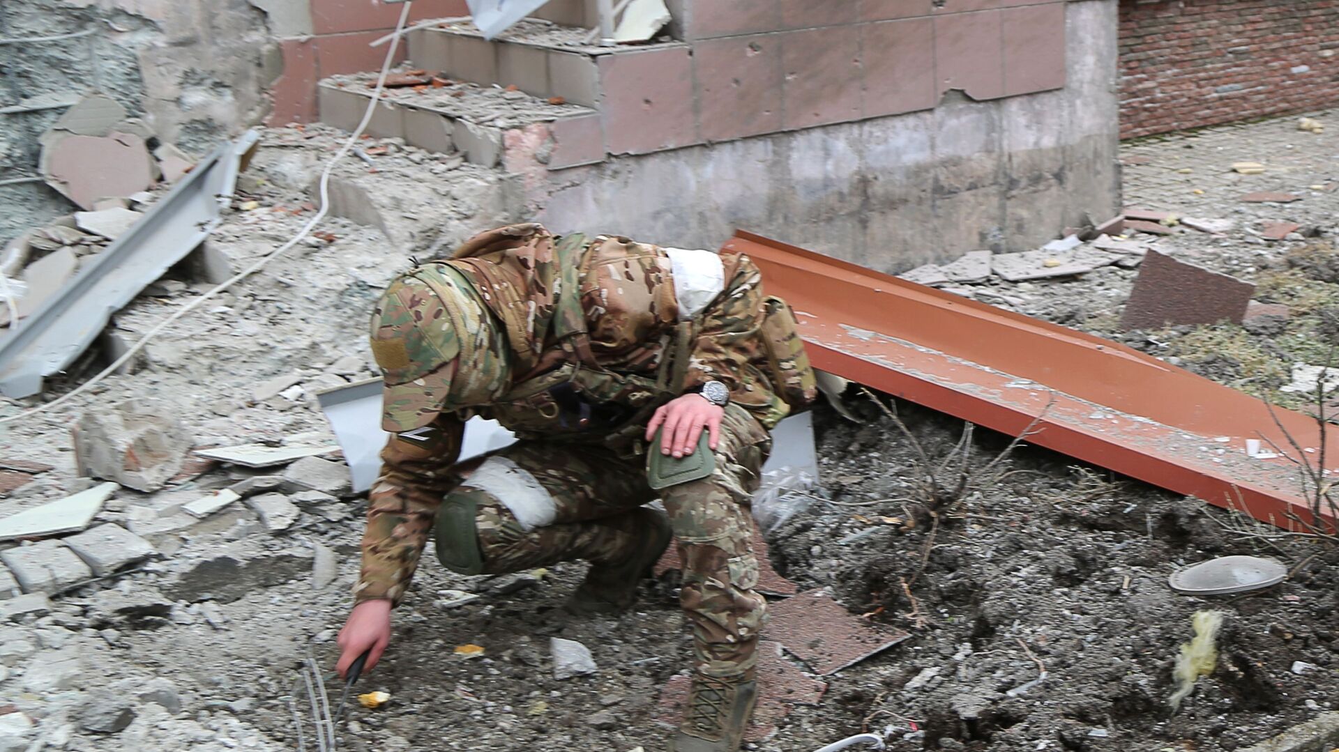 Военнослужащий обследует воронку от взрыва во дворе многоэтажного жилого дома в Донецке, поврежденного в результате обстрела - اسپوتنیک افغانستان  , 1920, 14.03.2022