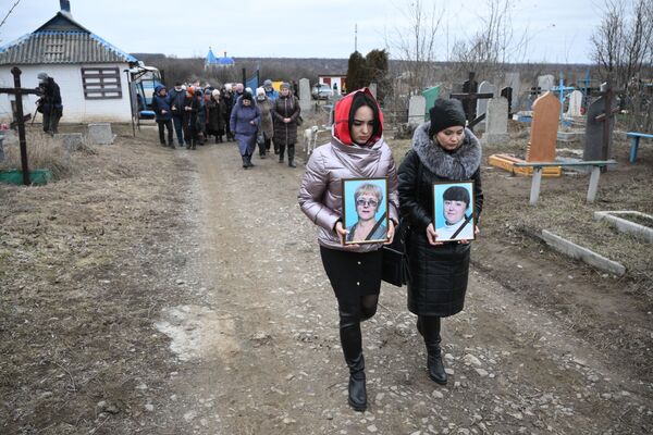 زنان عکس هایی از کسانی را  که در جریان گلوله باران ساختمانی در گورلووکا در دونتسک توسط سربازان اوکراینی جان خود را از دست دادند، حمل می کنند. - اسپوتنیک افغانستان  