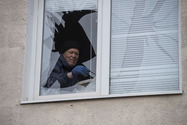 مردی تکه های شیشه را از یک پنجره شکسته در یک ساختمان مسکونی در جمهوری خلق لوهانسک جدا می کند. - اسپوتنیک افغانستان  