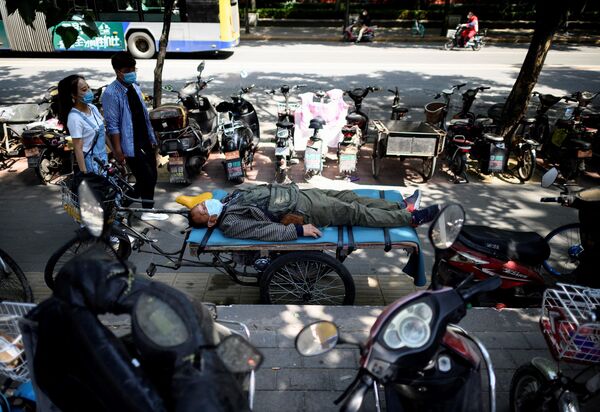 مردی با ماسک صورت روی تخت سه چرخه در پکن. - اسپوتنیک افغانستان  