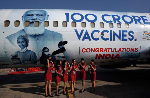 مهماندار اسپایس‌جت در حین رونمایی از هواپیمای ویژه برای نشان دادن 1 میلیارد دوز نقطه عطف واکسن کووید-19 در دهلی نو، هند، ماسک ها را برای گرفتن عکس برداشتند. - اسپوتنیک افغانستان  