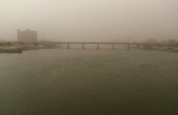 این تصویر که در 16 آگوست 2022 گرفته شده است نمایی از پلی بر روی رودخانه دجله در بغداد پایتخت عراق را در میان طوفان گرد و غبار نشان می دهد. - اسپوتنیک افغانستان  