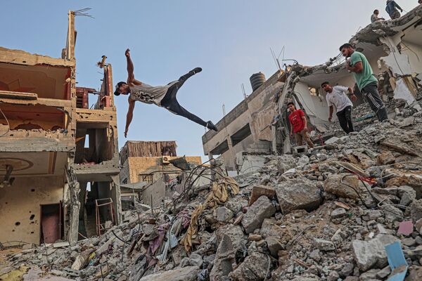 جوانان فلسطینی در میان آوار ساختمان‌هایی که در نتیجه آخرین حملات اسرائیل در جنوب نوار غزه تخریب شدند - اسپوتنیک افغانستان  