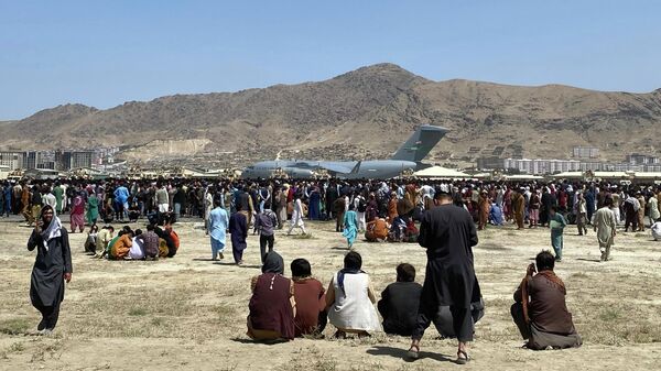  In this Aug. 16, 2021, file photo, hundreds of people gather near a U.S. Air Force C-17 transport plane at the perimeter of the international airport in Kabul, Afghanistan. Ordinary Americans and the nation's airlines are combining to donate miles and cash to help Afghan refugees resettle in the United States. Organizers said Tuesday, Oct. 26, they have raised enough donations pay for 40,000 flights, but they're hoping to nearly double that amount.  - اسپوتنیک افغانستان  