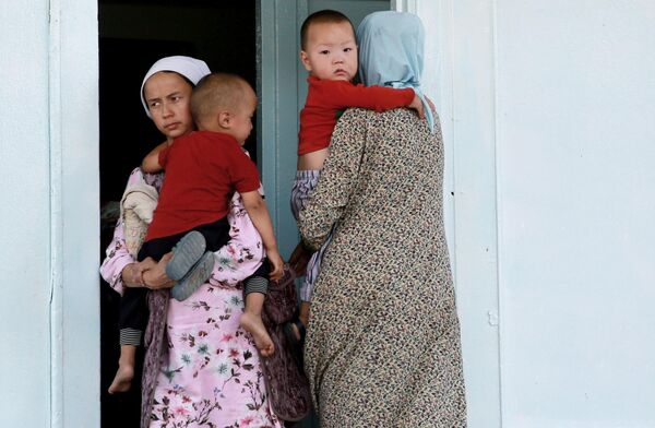 پناهندگان در دروازه تعمیر مکتب قصبه بوز ادیر که به محل اقامت موقتی شان شده است. - اسپوتنیک افغانستان  