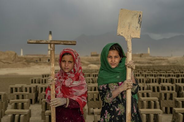 دو دختر در یکی از کارخانه های خشت در حومه شهر کابل، با وسایل کاری شان عکس میگیرند.  - اسپوتنیک افغانستان  