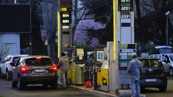 Работник меняет цены на топливо на табло на заправочной станции в Милане - اسپوتنیک افغانستان  
