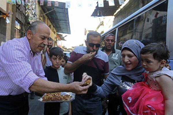 یک فروشنده در حالی که سوری ها ولادت حضرت محمد (ص) را جشن می گیرند، که در عربی به عنوان عید &quot;مولید النبی&quot; شناخته می شود، در بازاری در پایتخت دمشق در 8 اکتوبر 2022، شیرینی می دهد. - اسپوتنیک افغانستان  