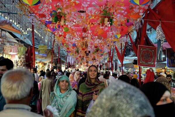 مردم در بازاری که برای جشن مولد النبی تزیین شده است، جشن میلاد پیامبر اسلام محمد، در لاهور، پاکستان، جمعه، 7 اکتبر 2022، تزیین شده است. هزاران مسلمان پاکستانی در 9 اکتوبر در مراسم مذهبی شرکت نمودند و غذای رایگان را بین فقرا تقسیم کردند. - اسپوتنیک افغانستان  