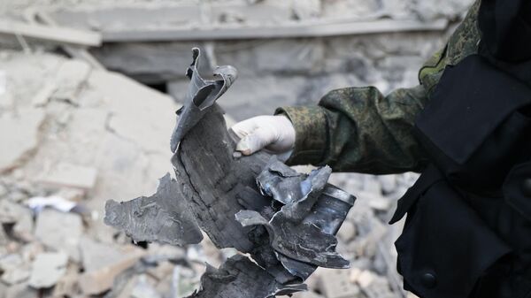 Следователь СЦ РФ демонстрирует часть снаряда на месте пострадавшего в результате обстрела со стороны ВСУ здания городской администрации в центре Донецка - اسپوتنیک افغانستان  