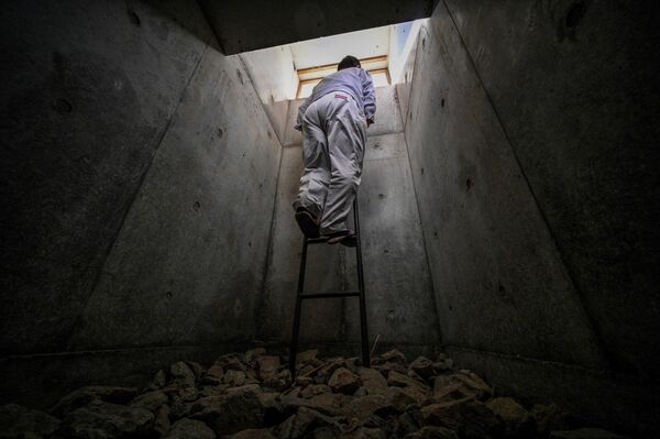 در این عکس یکی از کارمندان شرکت نوکوبه اوریبه بنام فومیه ماتسوتانی، ئذ حال خروج از نردبان اطظراری این پناهگاه زیرزمینی است. - اسپوتنیک افغانستان  