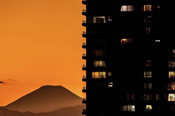 کوه فوجی (بک ایل)، مرتفع‌ترین کوه جاپان، در پشت ساختمان‌های مسکونی کاوازاکی، از زمین بیسبال منطقه سبز تاماگاوا در توکیو در 26 اکتوبر 2022 دیده می‌شود. (عکس از فیلیپ فونگ / خبرگزاری فرانسه) - اسپوتنیک افغانستان  
