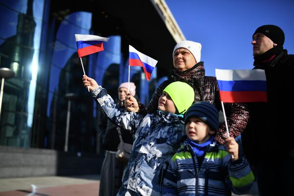 مردم در هنگام برداشتن پرچم روسیه در مقابل تالار کنسرت دولتی. نووسیبیرسک. - اسپوتنیک افغانستان  