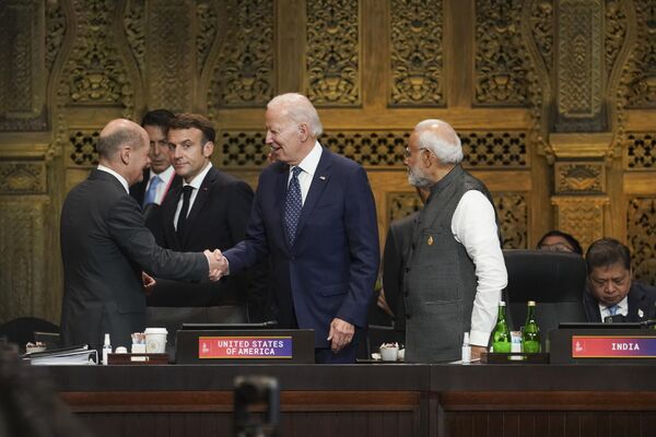 رئیس جمهور ایالات متحده امریکا جو بایدن با اولاف شولتس صدراعظم آلمان دست می دهد، در حالی که امانوئل مکرون رئیس جمهور فرانسه و نارندرا مودی نخست وزیر هند تماشا می کنند. نشست سران گروه 20 در نوسا دعا، اندونزی  - اسپوتنیک افغانستان  