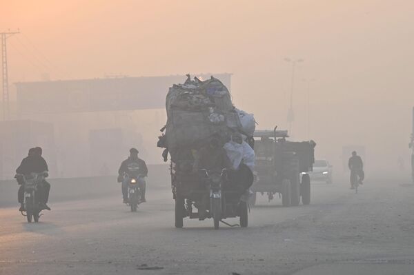 مسافران در 18 نوامبر 2022 در امتداد خیابانی در میان دود شدید در لاهور حرکت می کنند. - اسپوتنیک افغانستان  