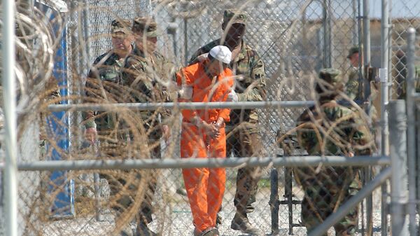 A detainee from Afghanistan is led by military police with his hands chained at Camp X-Ray at the U.S. Naval Base in Guantanamo Bay, Cuba, in this Feb. 2, 2002, file photo - اسپوتنیک افغانستان  
