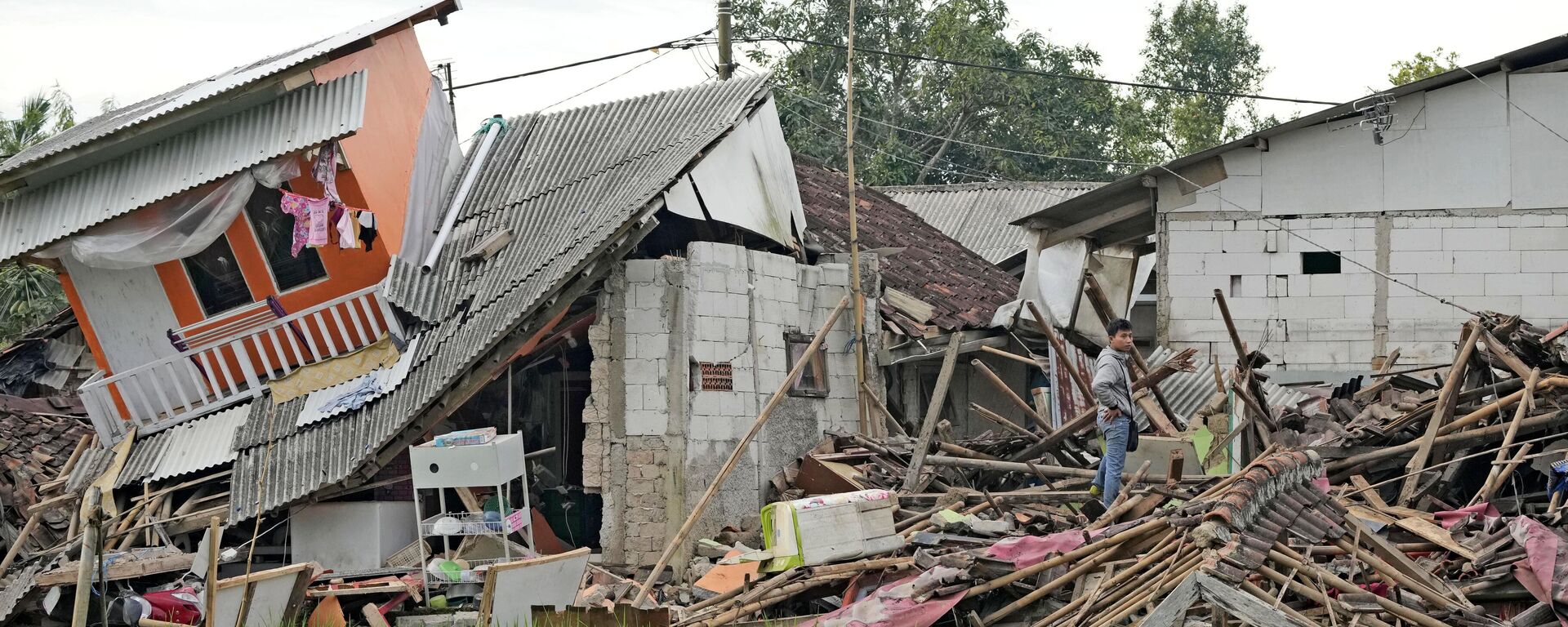 Мужчина осматривает поврежденные дома в районе, пострадавшем от землетрясения в Чианджуре, Западная Ява, Индонезия - اسپوتنیک افغانستان  , 1920, 22.11.2022