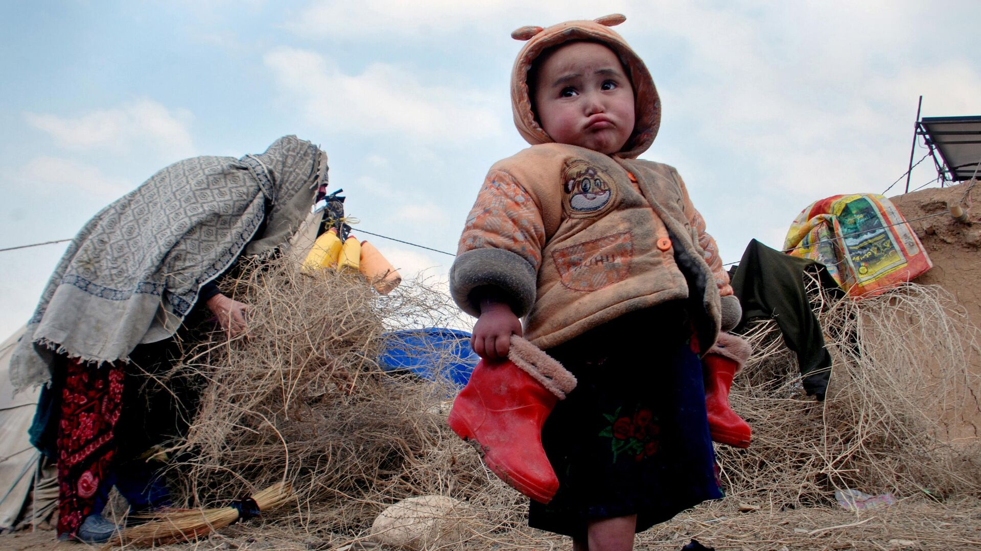 Афганский ребенок с сапожками в руках в лагере для внутренне перемещенных лиц на окраине Мазари-Шарифа, к северу от Кабула, Афганистан, 2014 год - اسپوتنیک افغانستان  , 1920, 14.12.2022
