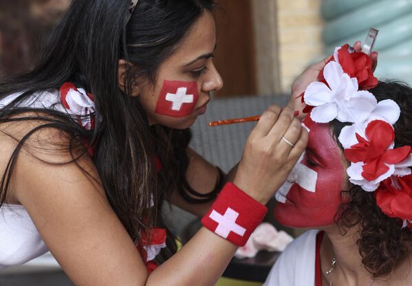 یک هوادار سوئیس در بازار سوق واقف در دوحه، پیش از مسابقه فوتبال جام جهانی قطر 2022 بین برازیل و سوئیس، در 28 نوامبر 2022، چهره خود را نقاشی می کند.  - اسپوتنیک افغانستان  